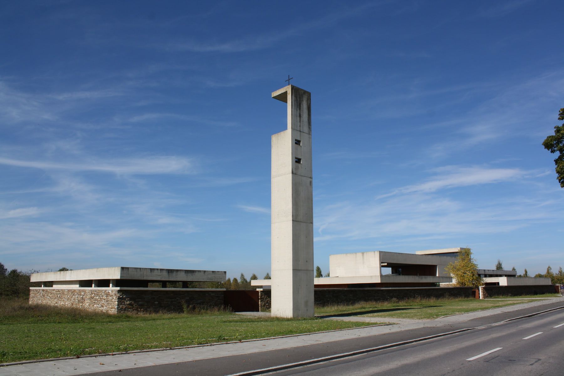 Low modern building complex with a slender freestanding bell tower at Riem Cemetery